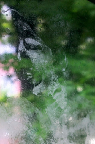 Gesichtabdruck auf Glasscheibe vor grünem Hintergrund